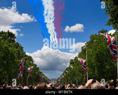 Red Arrows flypast with tricolour streamers at The Mall with Union Jack flags and crowds for Trooping the Colour Queen’s Birthday 2019 London England Stock Photo