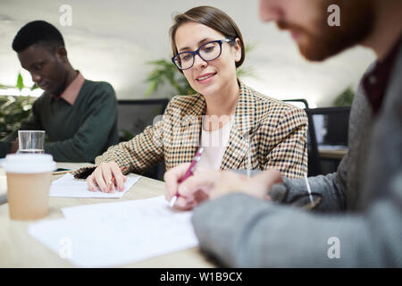 Portrait of young businesswoman looking at plans during meeting in office, copy space Stock Photo