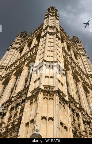 Looking up to newly renovated Victoria Tower of the Palace of Westminster London United Kingdom with overhead jet plane Stock Photo