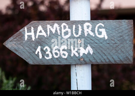 grey sign with white font on a white pole which points to Hamburg Stock Photo