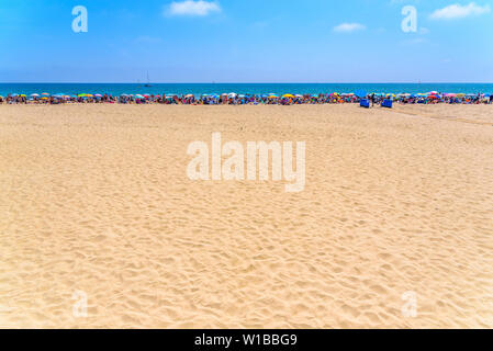 Valencia, Spain - June 23, 2019: Bathers with their beach umbrellas on the front line sunbathing. Stock Photo