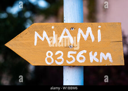 yellow sign with white font on a white pole which points to Miami Stock Photo
