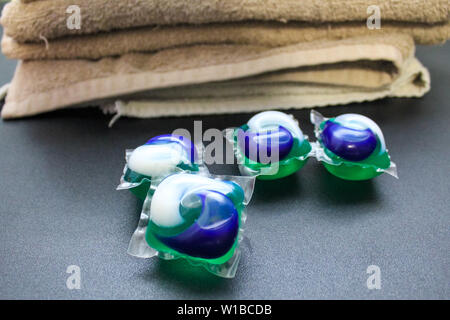 Laundry Day - laundry detergent pods on a laundry folding table with tan towels. Stock Photo