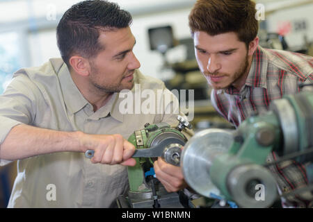 engineer teaching apprentices using metal processing machines Stock Photo