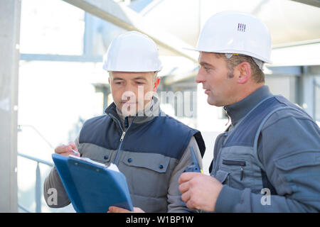 serios adult men engineer talking over clipboad Stock Photo