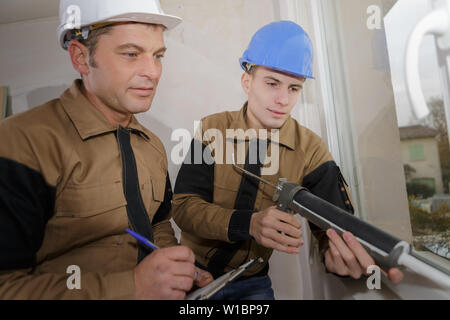 young construction worker being tested while installing window Stock Photo
