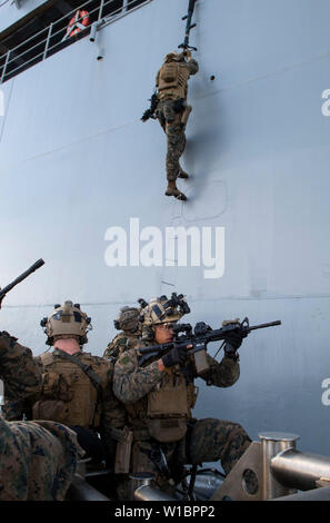 190623-N-DX072-1173 PACIFIC OCEAN (June 23, 2019) Marines assigned to the 31st Marine Expeditionary Unit (MEU) Maritime Raid Force board the amphibious dock landing ship USS Ashland (LSD 48) from a Rigid-Hull Inflatable Boat (RHIB) assigned to the amphibious transport dock ship USS Green Bay (LPD 20) as part of a visit, board, search and seizure (VBSS) rehearsal. Green Bay and Ashland, part of the Wasp Amphibious Ready Group, with embarked 31st MEU, are operating in the Indo-Pacific region to enhance interoperability with partners and serve as a ready-response force for any type of contingency Stock Photo
