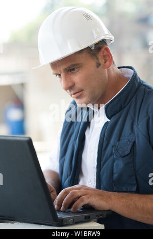 adult male engineer managing process with laptop Stock Photo