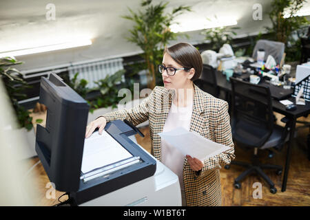 High angle portrait of young businesswoman scanning documents while working in office, copy space Stock Photo