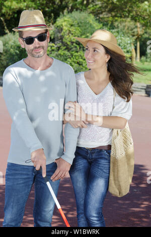 young woman and blind man in the park Stock Photo