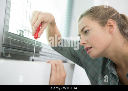 woman installing blinds with screwdriver Stock Photo