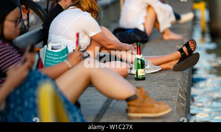 Berlin, Germany. 01st July, 2019. People sit in the evening at the East Side Gallery on the Spree. Credit: Paul Zinken/dpa/Alamy Live News Stock Photo