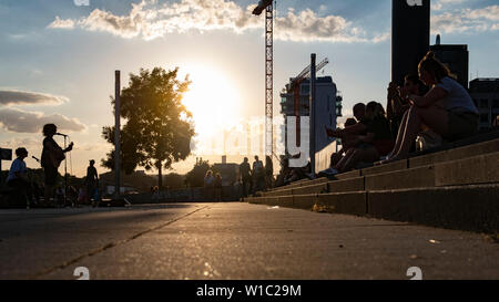 Berlin, Germany. 01st July, 2019. In the evening people sit at the East Side Gallery and listen to two street musicians. Credit: Paul Zinken/dpa/Alamy Live News Stock Photo