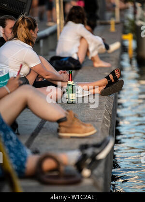 Berlin, Germany. 01st July, 2019. People sit in the evening at the East Side Gallery on the Spree. Credit: Paul Zinken/dpa/Alamy Live News Stock Photo