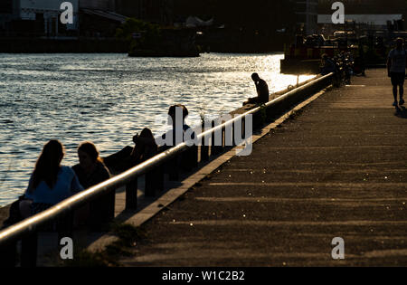 Berlin, Germany. 01st July, 2019. People sit in the evening at the East Side Gallery on the Spree. Credit: Paul Zinken/dpa/Alamy Live News Stock Photo