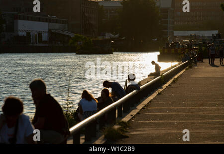 Berlin, Germany. 01st July, 2019. People sit in the evening at the East Side Gallery on the Spree. Credit: Paul Zinken/dpa/Alamy Live News Stock Photo