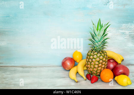 A pile of fresh fruits in front of a blue rustic wooden background. Stock Photo