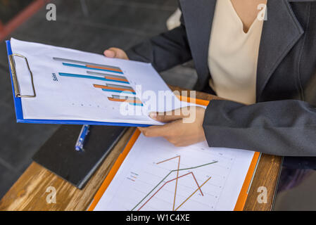 Close up of woman wearing black suit holding sales chart  Stock Photo