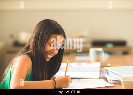 Young Girl Sitting At A Desk And Working On Her Homework Stock Photo