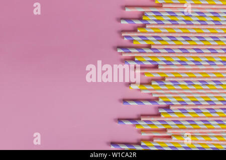 row of drinking straws with stripe and polka dot design border on pink background.prohibition of the use of plastic.Minimalism concept. Pop art style Stock Photo