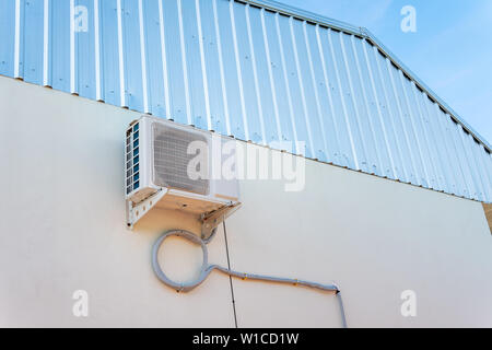 Air conditioner compressor unit on white wall, outdoor. Stock Photo