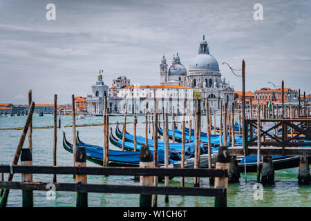 Venice view on Santa Maria della Salute basilica and gondolas on the Grand canal. Famous tourist attraction, summer city trip.