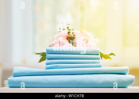 Closeup stack of blue clean bedding on the table. Blurred background. Stock Photo