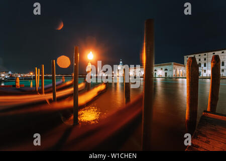 Amazing night urban landscape from Venice city canal with gondolas anchored on Grand Canal in Venice - long exposure night shot with motion blurred Stock Photo