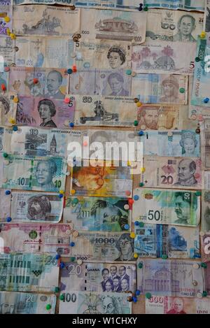 Collection of different banknotes from a variety of countries pinned on a notice board. Stock Photo