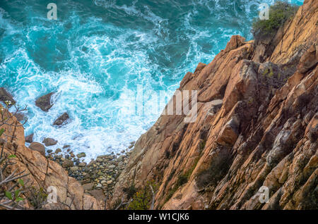 Blue sea with rocky coast at the bottom of cliff. Stock Photo