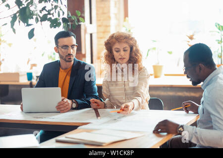 Speaking to boss. Two experienced interior designers speaking about new project to boss Stock Photo