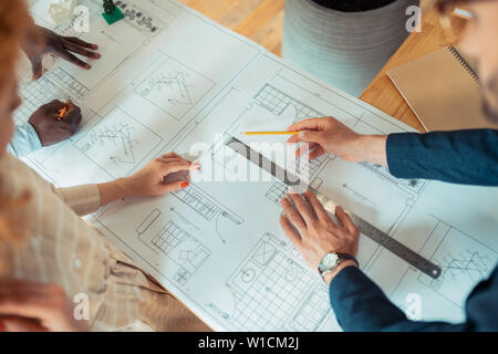 Ruler and pencil. Men and woman using ruler and pencil while drawing sketches for new project Stock Photo