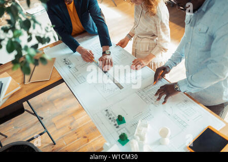 Designers cooperating. Top view of men and woman cooperating while drawing sketches for project Stock Photo