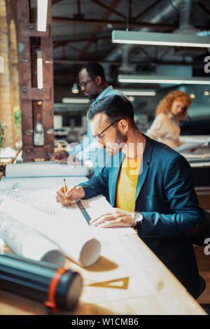 Feeling busy. Interior designer wearing glasses feeling busy while working on sketches Stock Photo