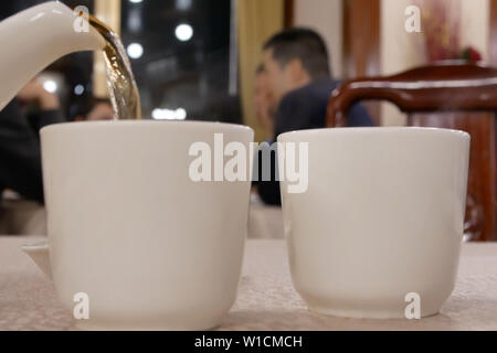 Motion of people pouring hot tea inside Chinese restaurant Stock Photo