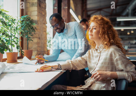 Stylish designer. Stylish blue-eyed interior designer wearing nice dress working in team Stock Photo