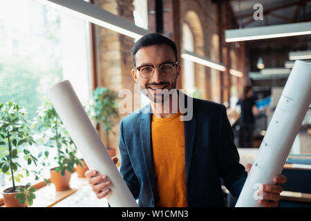 Interior designer smiling. Handsome bearded interior designer smiling after finishing making sketches Stock Photo