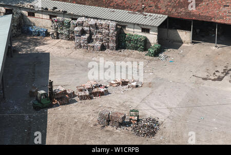 Industrial garbage sorting. Forklift forms blocks of plastic and paper for recycling Stock Photo