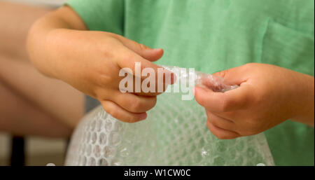 Childrens hands burst bubbles polyethylene Stock Photo