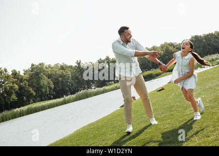 Best father ever Happy young father and daughter holding hands and smiling while walking near the river. Love and family concept Stock Photo