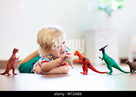 Child playing with colorful toy dinosaurs. Educational toys for kids. Little boy learning fossils and reptiles. Children play with dinosaur toys. Evol Stock Photo