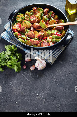 Vegetable Ratatouille with chicken meat in a black ceramic pan on a concrete table, vertical view from above Stock Photo
