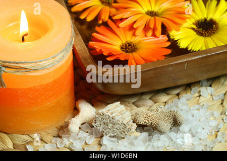 Beautiful natural spa composition. Marigold flowers floating in wooden bowl, corals and candle light Stock Photo