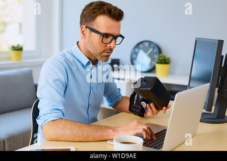 Game developer working on laptop creating VR virtual reality game Stock Photo