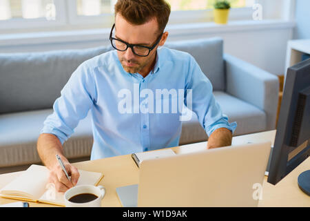 Young man working by the desk from his home office Stock Photo