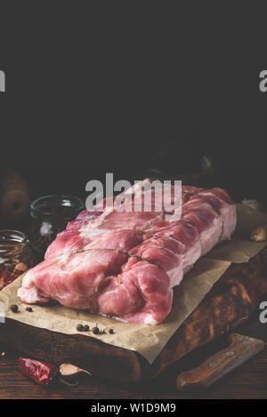 Raw pork loin joint on cutting board with different spices Stock Photo
