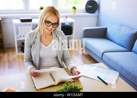 Happy woman working from home office with documents Stock Photo