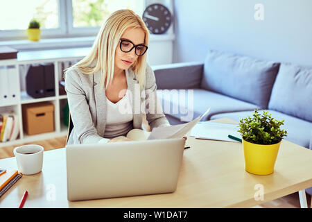 Thoughtful young woman looking on documents, working from home office Stock Photo