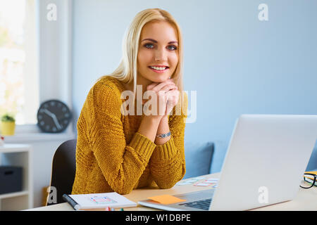 Happy young female designer working from home office Stock Photo