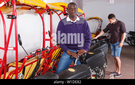 Successful African American driver of pedicab offering touristic tour Stock Photo